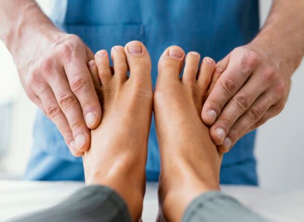 vista-frontal-del-terapeuta-osteopatico-masculino-comprobando-los-dedos-de-los-pies-del-paciente-femenino vista-frontal-del-terapeuta-osteopatico-masculino-comprobando-los-dedos-de-los-pies-del-paciente-femenino