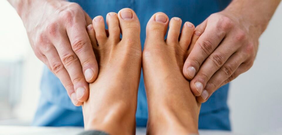 vista-frontal-del-terapeuta-osteopatico-masculino-comprobando-los-dedos-de-los-pies-del-paciente-femenino
