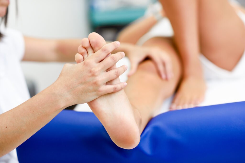 Medical massage at the foot in a physiotherapy center. Female physiotherapist inspecting her patient.